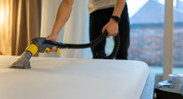 man cleaning a mattress with vacuum cleaner