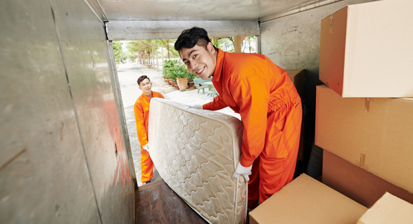 two young men lifting a mattress into van